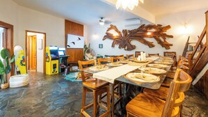 A dining area with a long wooden table set for a meal, surrounded by wooden chairs. - 🌴16 Bed Compound Oasis 🌴Downtown Jaco with Private Pool & Hot Tub (Jaco Beach)