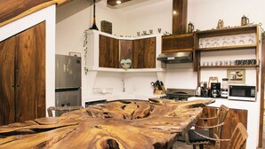 Une cuisine avec une table en bois, des chaises, un réfrigérateur, une cuisinière et divers appareils de cuisine.
