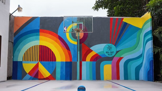 A basketball court with a colorful mural on the wall, a basketball hoop, and a ball on the court. - 🌴16 Bed Compound Oasis 🌴Downtown Jaco with Private Pool & Hot Tub (Jaco Beach)
