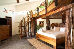 A rustic bedroom with a wooden bed, a ladder, and a TV on a dresser.