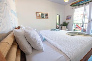 A bedroom with a bed, pillows, a quilted blanket, a wall-mounted mirror, and a door leading to an outdoor area.