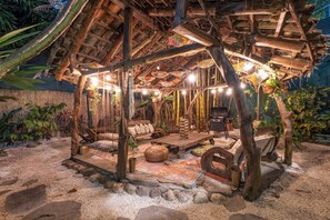 A rustic outdoor seating area with a thatched roof, wooden furniture, and hanging lights. - 🌴16 Bed Compound Oasis 🌴Downtown Jaco with Private Pool & Hot Tub (Jaco Beach)