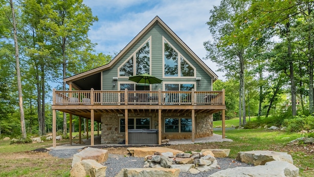 A two-story cabin with a balcony, stone foundation, and a stone fire pit. - Woods-stock (McHenry)