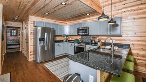 A modern kitchen with wooden walls, stainless steel appliances, and a granite countertop. - Woods-stock (McHenry)
