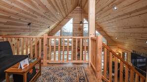 A wooden interior with a high ceiling, a staircase, and a view through large windows. - Woods-stock (McHenry)