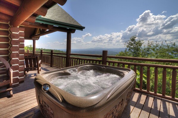 Ein Whirlpool auf einer Holzterrasse mit Blick auf Berge und Bäume.