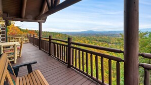 Une terrasse en bois avec une balustrade donnant sur un paysage pittoresque.