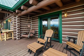 Eine Blockhütte mit einer Holzdiele, Sitzgelegenheiten im Freien und Blick auf die Landschaft.