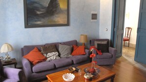 Un salón con un sofá morado, una mesa de centro de madera y un cuadro en la pared.