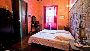Una habitación con una cama, muebles de madera, un escritorio y una pared de piedra.