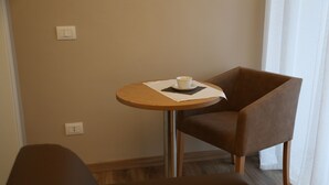 A small round table with a cup and saucer, a brown chair, and a light switch on the wall. - Montis (San Massimo)