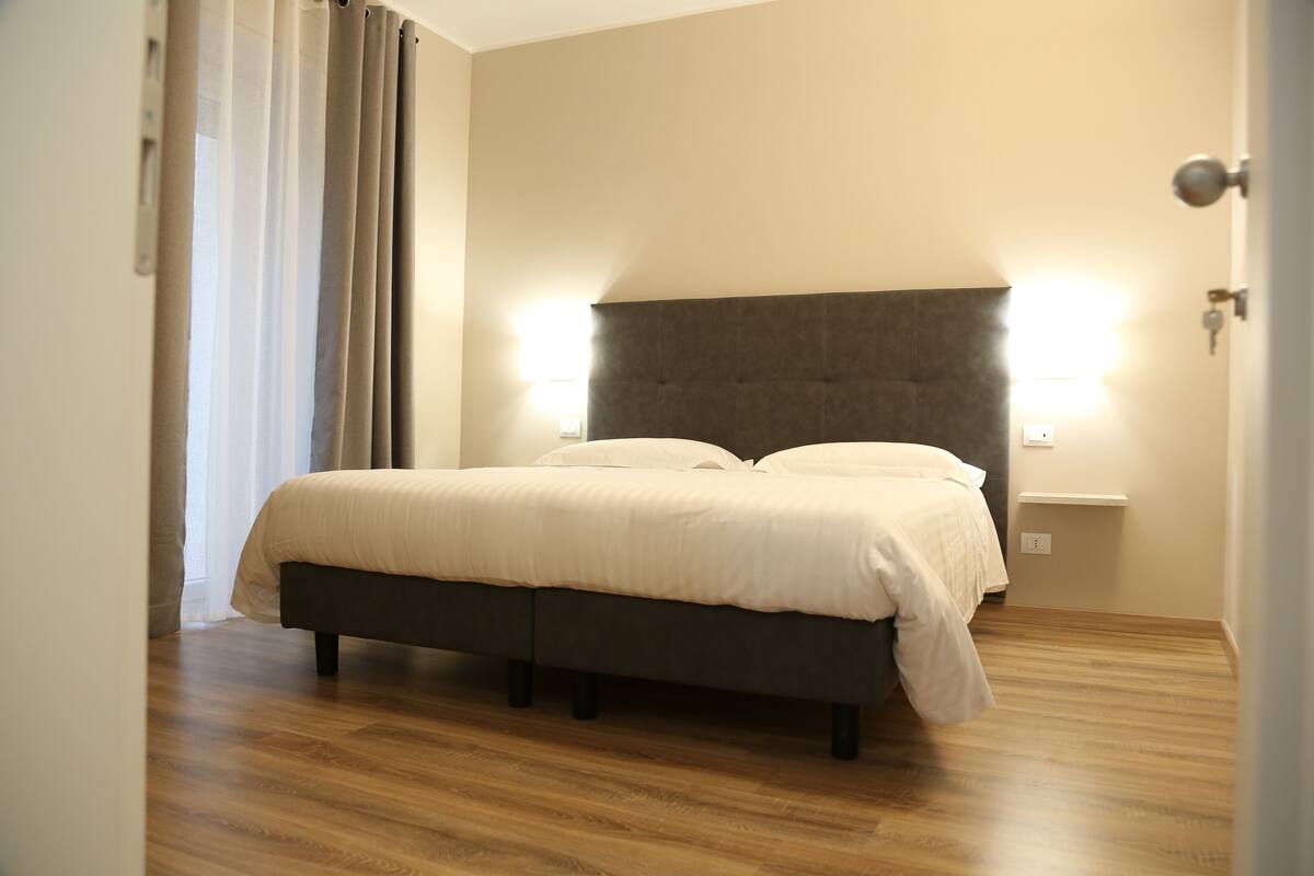 Une chambre à coucher avec un lit, un plancher en bois et deux lampes fixées au mur.