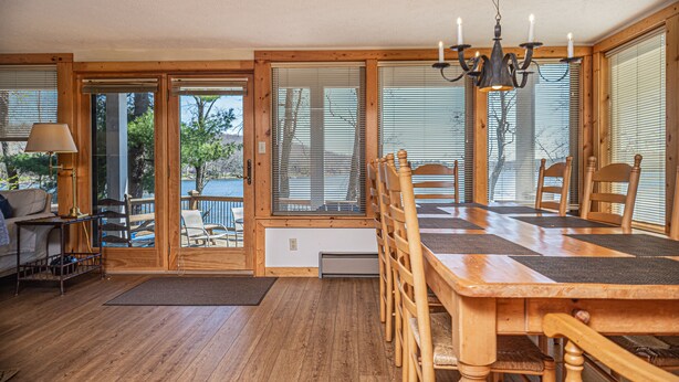 A wooden dining table with chairs, a chandelier, and a view of the outdoors through large windows. - Paradise Found (Oakland)