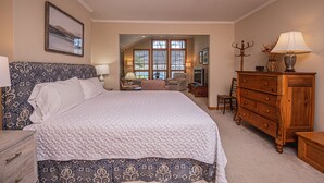 A bedroom with a large bed, a dresser, a chair, and a window. - Paradise Found (Oakland)