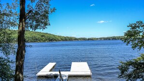A calm lake with two wooden docks extending into the water, surrounded by lush greenery and hills in the background. - Paradise Found (Oakland)