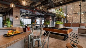 Zona de bar moderna con mesa de billar, taburetes y una hamburguesa en la barra.