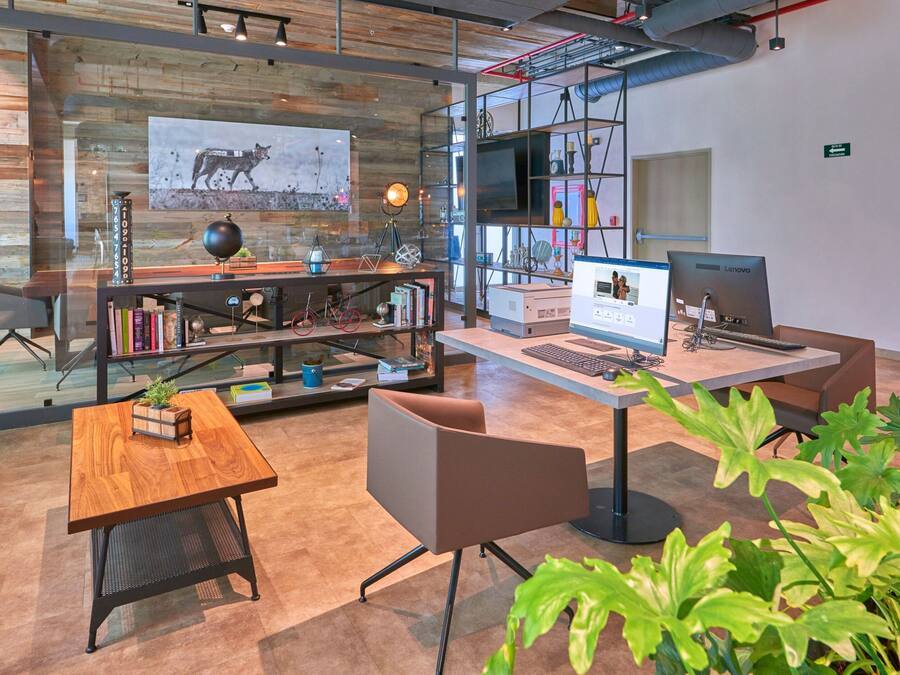 Un espacio de oficina moderno con un escritorio de madera, dos sillas, una estantería y un equipo informático.