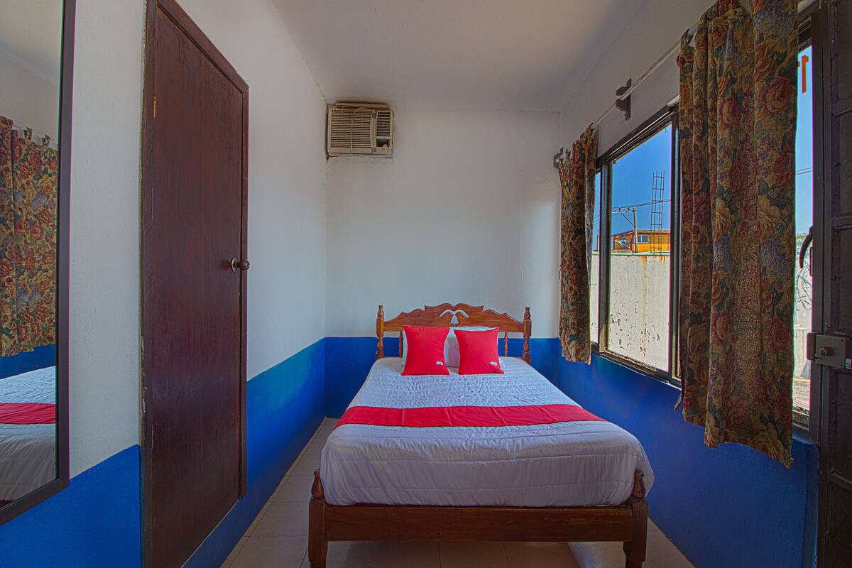 A bedroom with a wooden bed, a window with curtains, and a door.