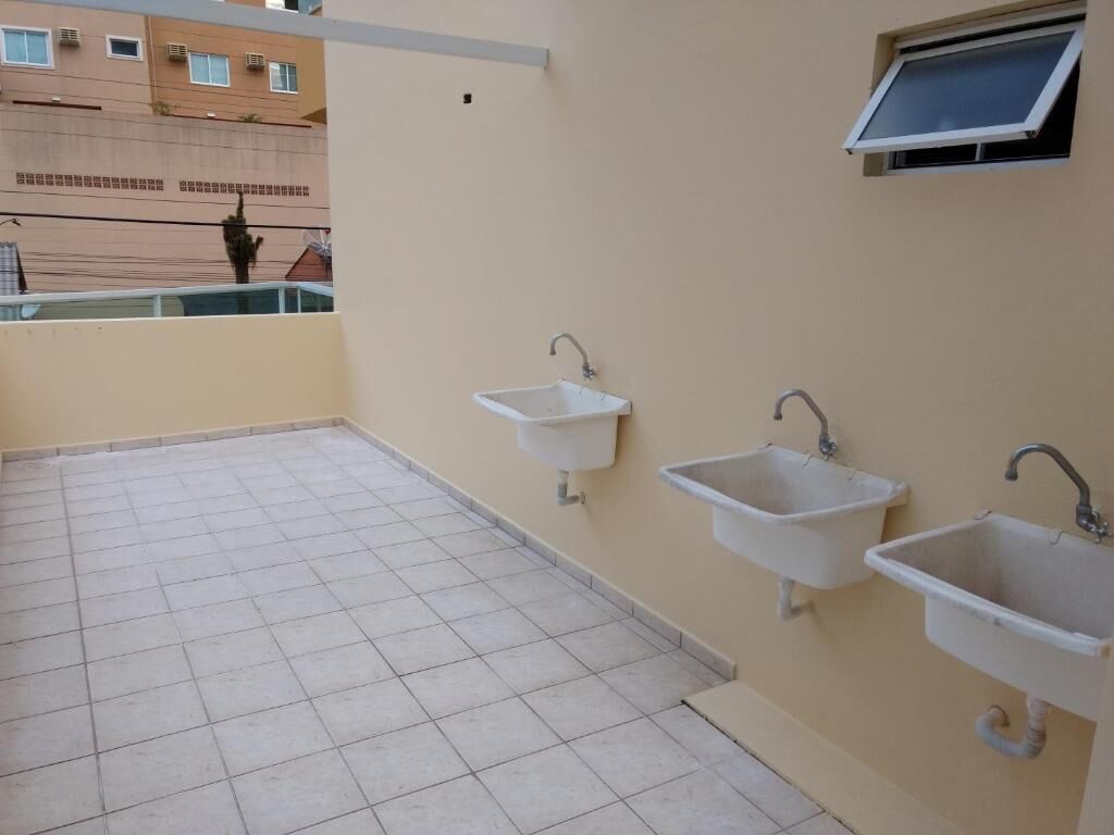 A balcony with three white sinks and a window.