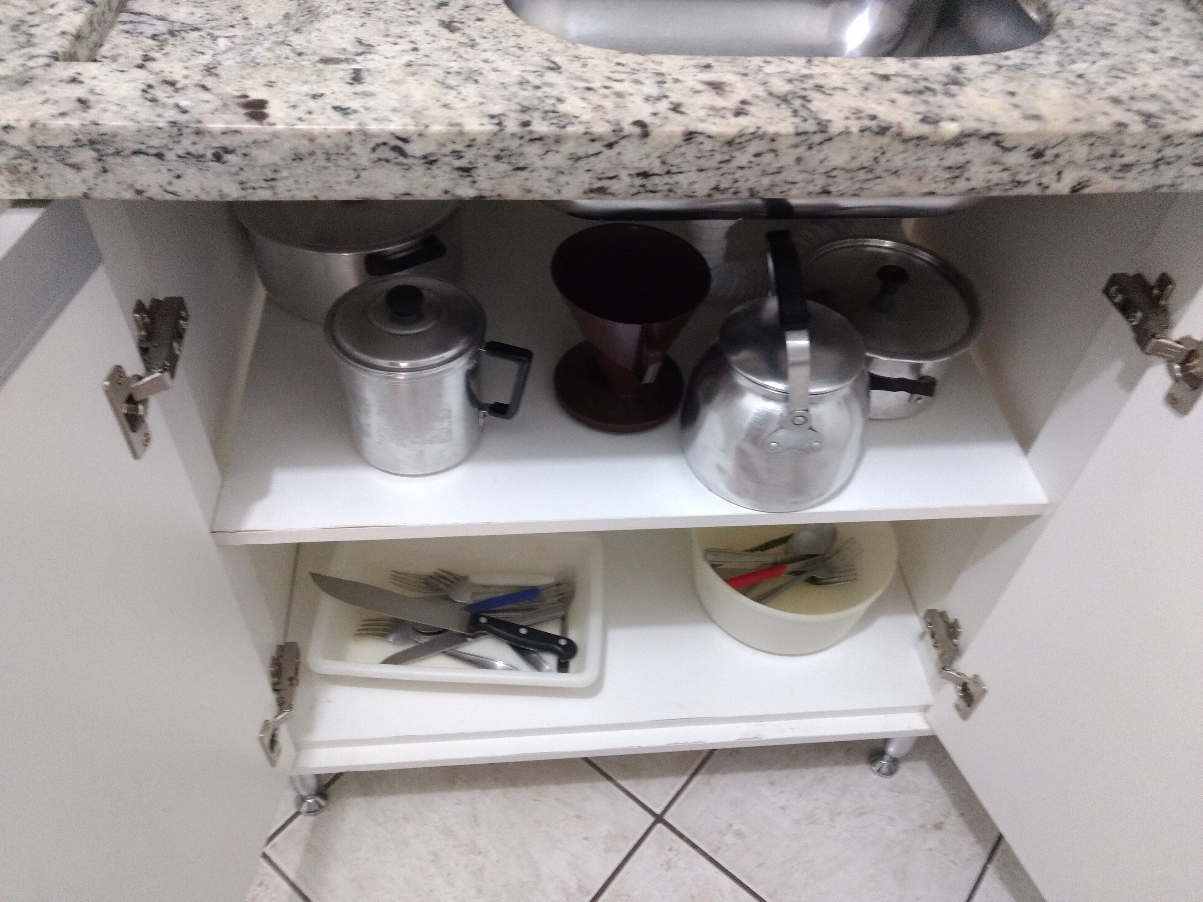 Una cocina con encimeras de granito, un hervidor de acero inoxidable, una cafetera y un utensilero.