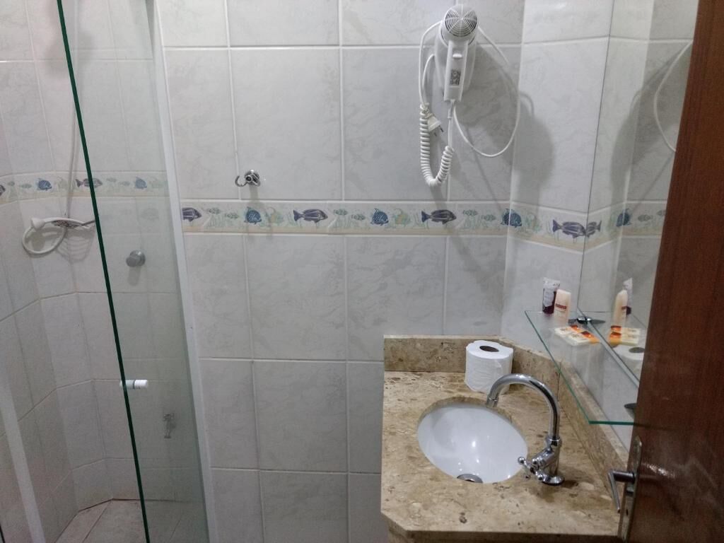 A bathroom with a glass shower enclosure, a sink with a marble countertop, and a towel rack.