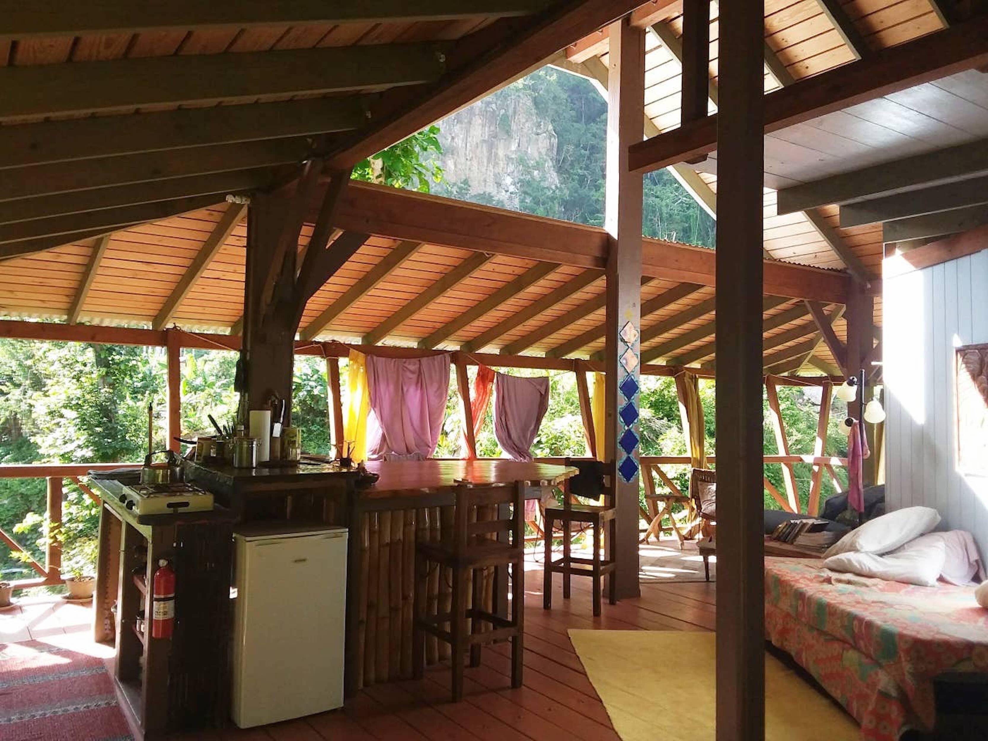A wooden cabin with a kitchen area, a dining table, and a bed.