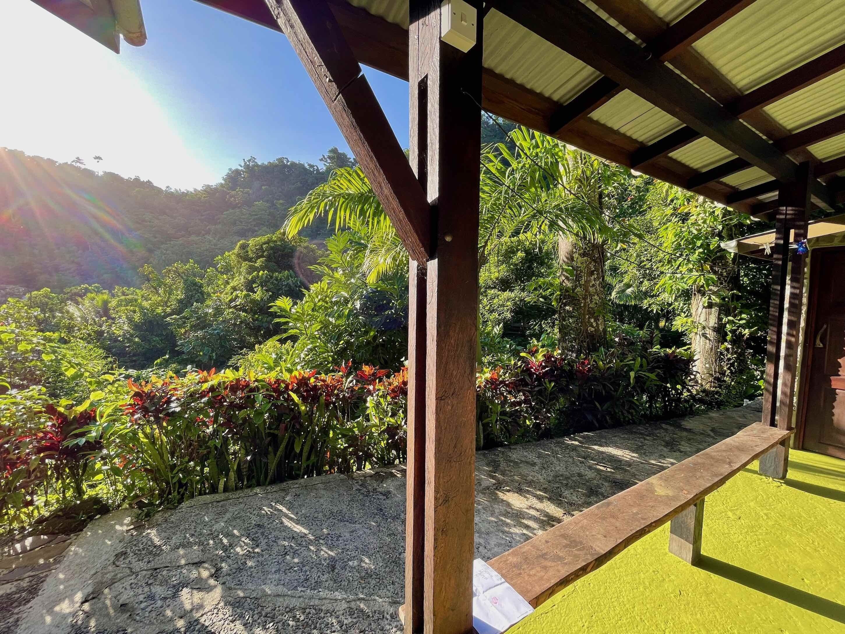 A covered outdoor area with a view of a lush garden and hills in the background.