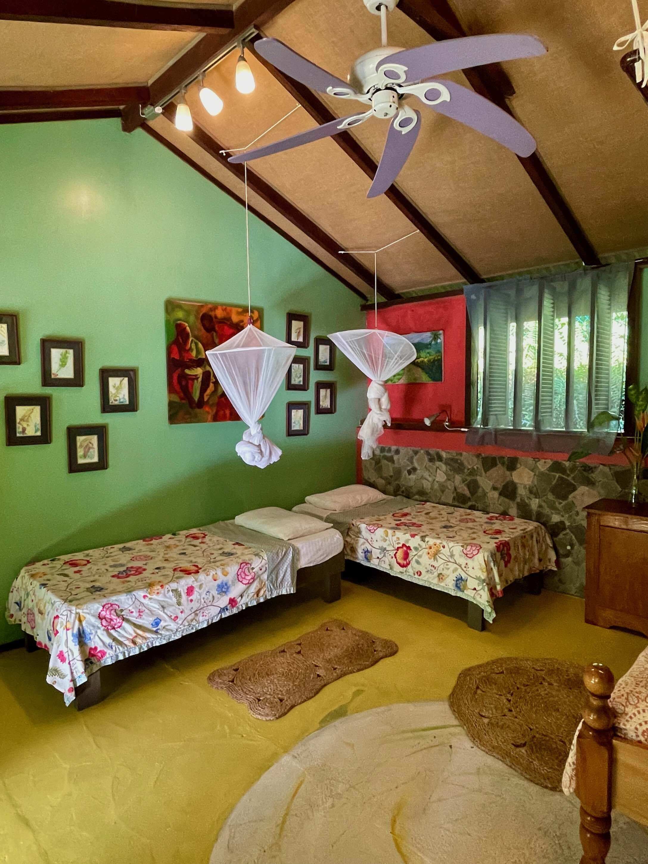 A room with two single beds, a ceiling fan, and a window with curtains.