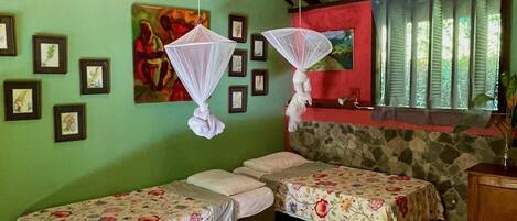A room with two single beds, a ceiling fan, and a window with curtains.
