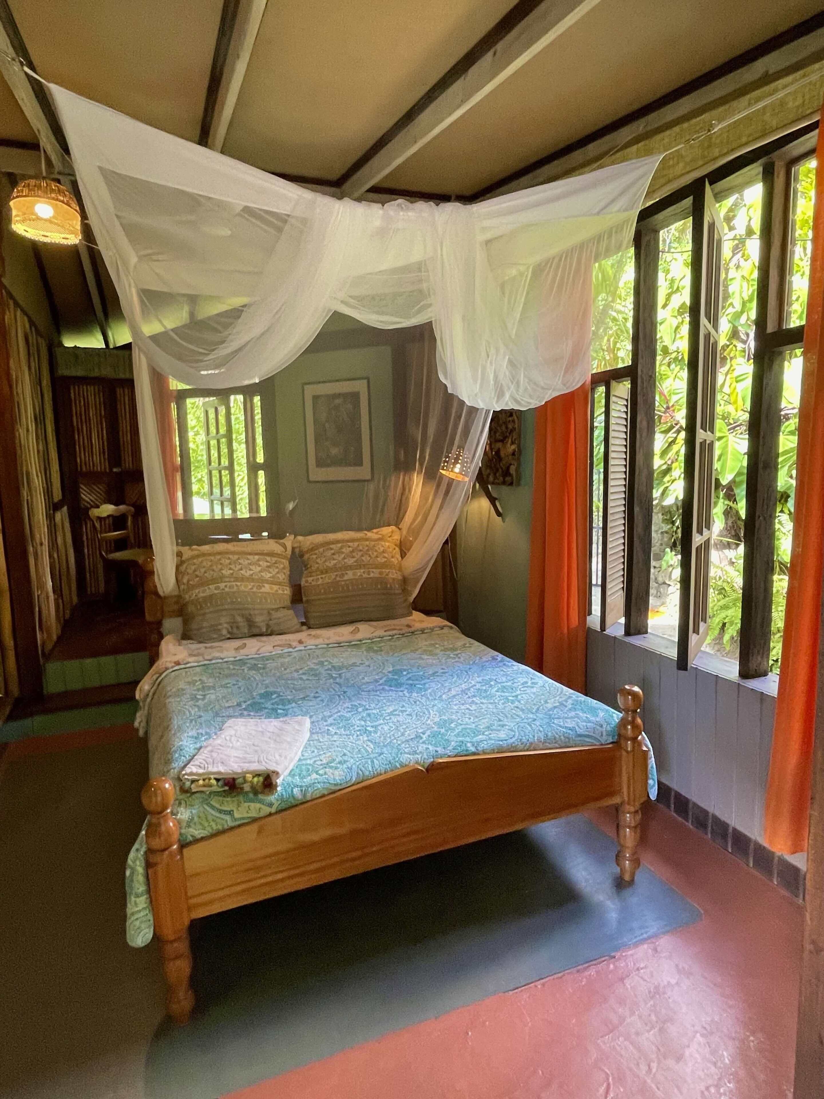 Una cama con dosel, una ventana con persianas y un cuadro en la pared.