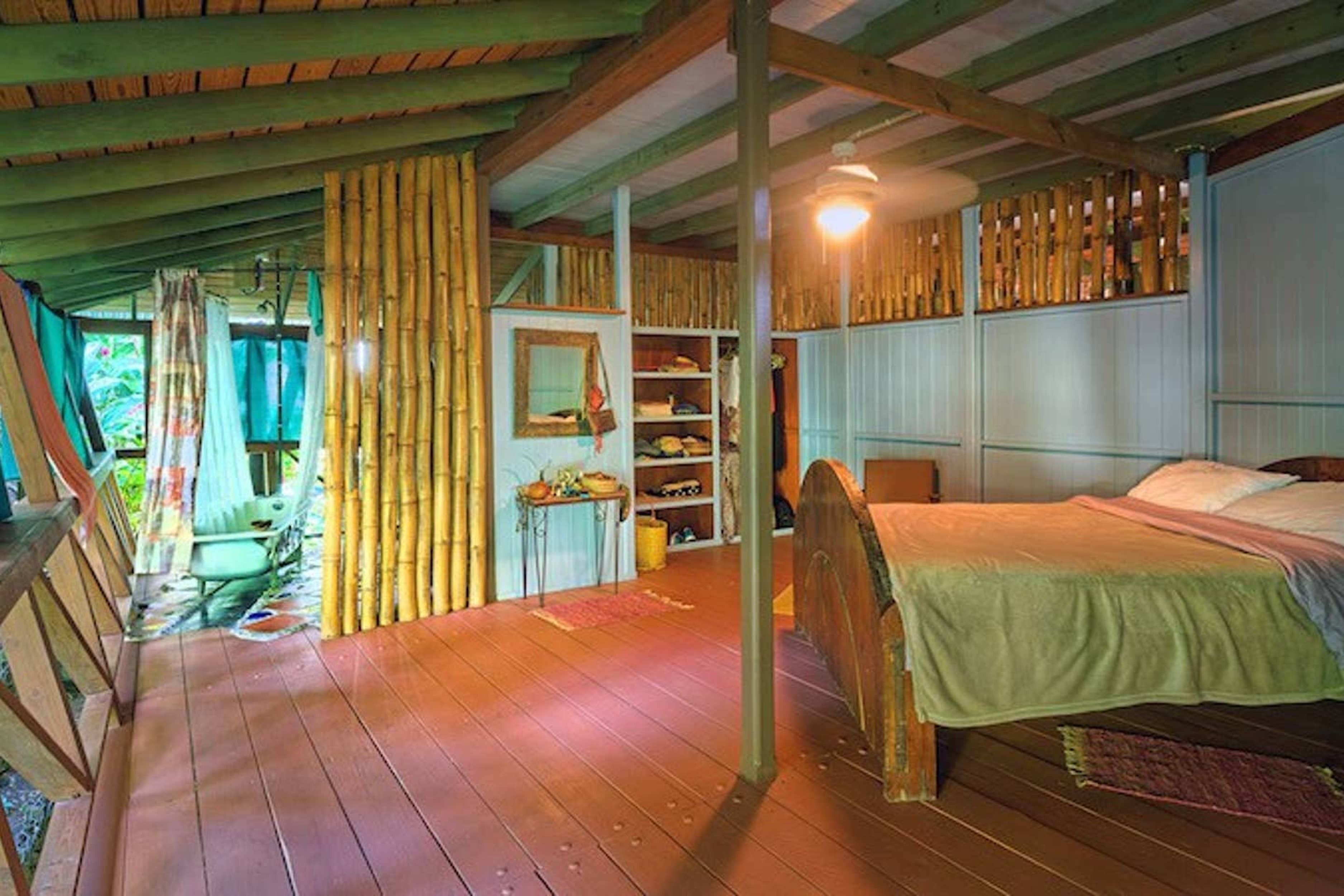 A wooden interior with a bed, shelves, and a hanging light fixture.