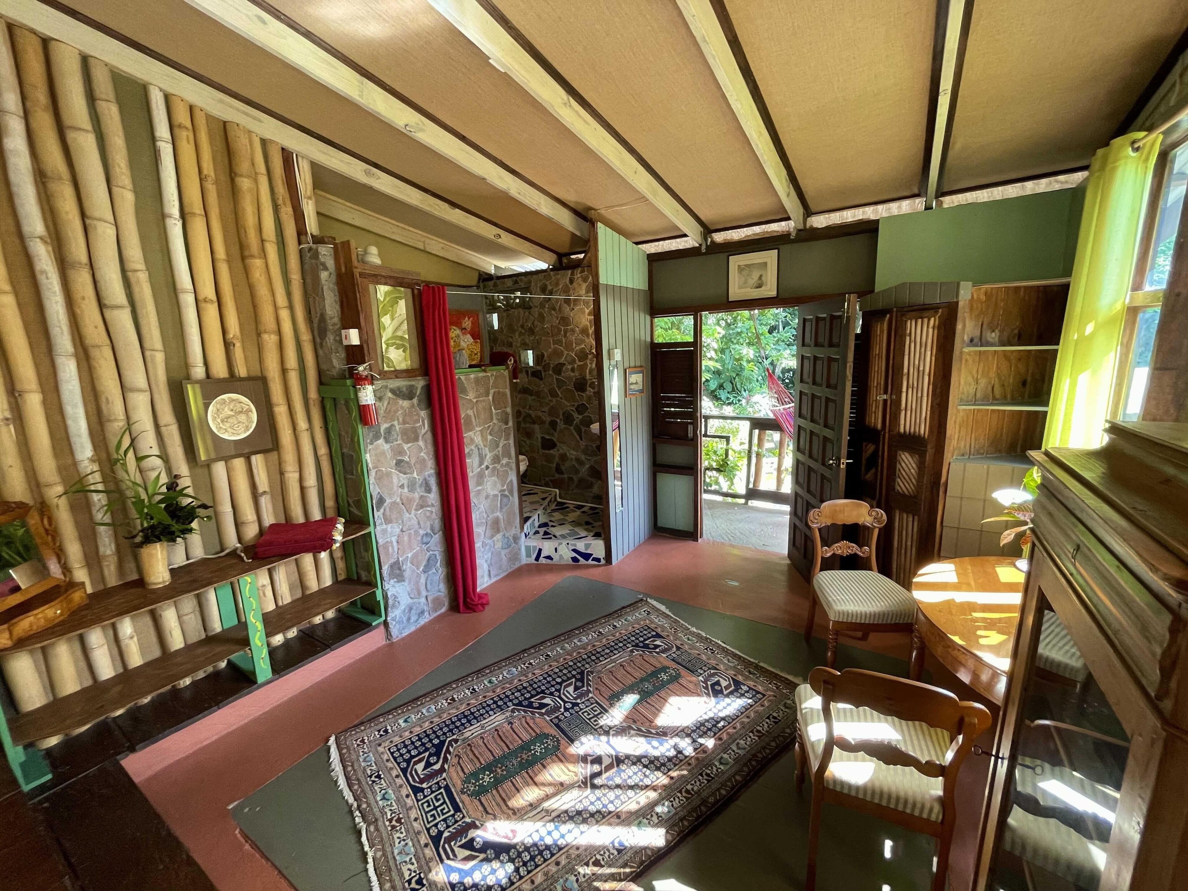 A room with a bamboo wall, a patterned rug, a wooden chair, and a bookshelf.