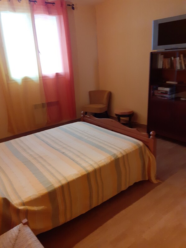 Une chambre à coucher avec un lit, une chaise, une petite table et une bibliothèque.