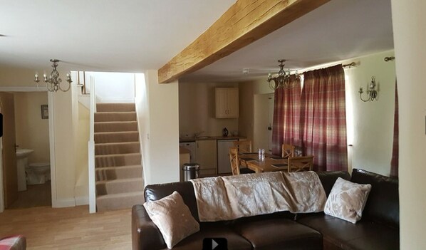 Relax in this inviting living space with a cozy sofa, dining area, and staircase leading to additional living space.