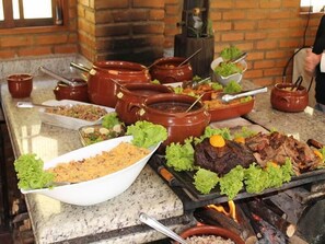 A buffet table with various dishes, including meats and salads, served on a granite countertop. - Hotel Rural Vale das Nascentes (Salesopolis)