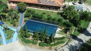 A building with a large solar panel array, a swimming pool, and a covered outdoor area. - Hotel Rural Vale das Nascentes (Salesopolis)