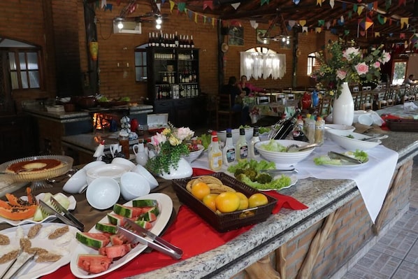 A buffet setup with various food items and condiments, including watermelon, oranges, and a variety of dishes.