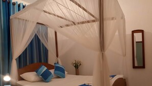 Ein Himmelbett mit Baldachin, ein Nachttisch mit Lampe und ein Spiegel an der Wand.