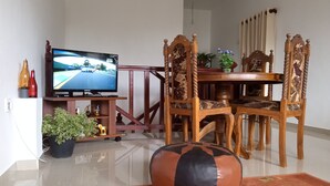 Ein Wohnzimmer mit Fernseher, einem Holzesstisch, Stühlen, einer Couch und einem dekorativen Teppich.