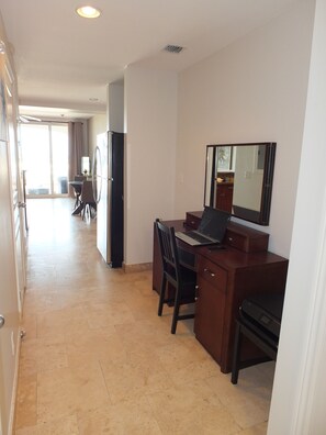 A hotel room with a desk, chair, and a large mirror. There is a dining area with a table and chairs in the background. - PROVO PARADISE - Junior CondoSuite (Cooper Jack Bay Settlement)