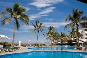 A swimming pool with palm trees and lounge chairs.
