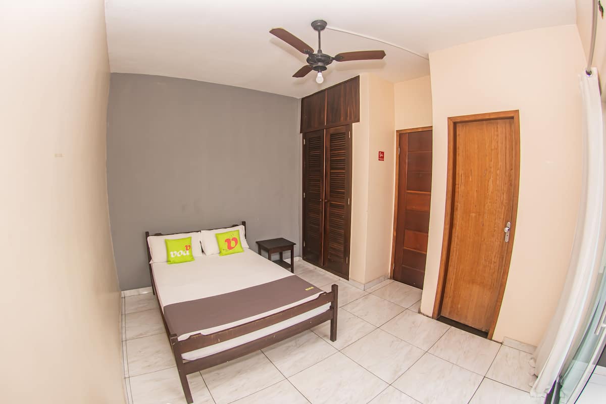Un dormitorio con cama, ventilador de techo, armario y una puerta.