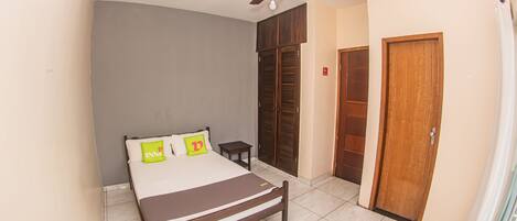 A bedroom with a bed, a ceiling fan, a wardrobe, and a door.