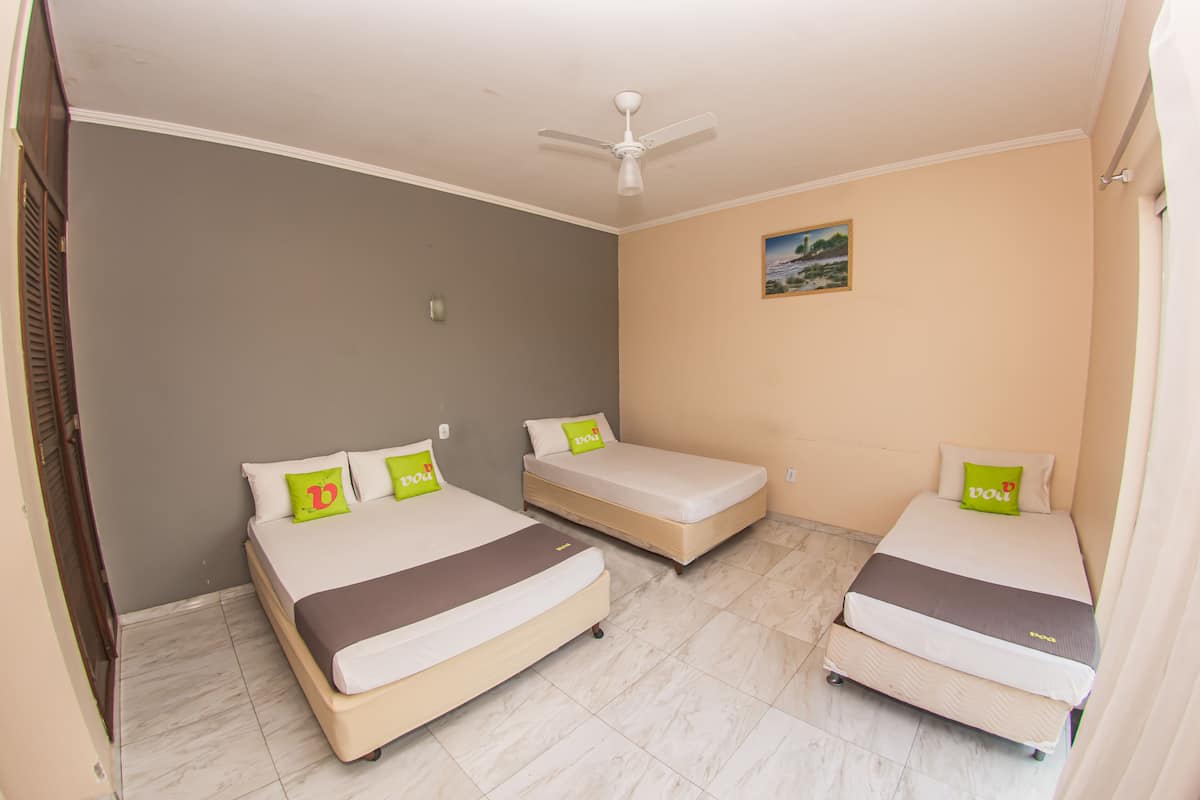 Una habitación con tres camas, un ventilador de techo y un cuadro en la pared.