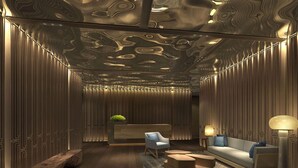 Een modern interieur met een receptiebalie, een zithoek en een gestreept plafond.