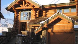 Une cabane en rondins avec des fondations en pierre, un revêtement extérieur en bois et un garage.