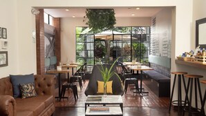 Un intérieur moderne avec un canapé en cuir, une table basse avec des livres et un coin salon comprenant des tables et des chaises.
