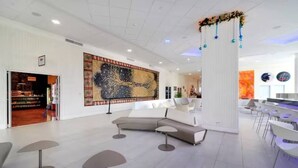 Un'ampia hall con un grande dipinto astratto, un'area salotto moderna e un bar con sgabelli.