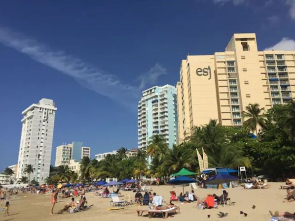 Ein Strandhotel mit mehreren Hochhäusern, Palmen und Badegästen.