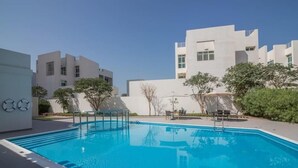 Una piscina con superficie d'acqua cristallina e azzurra, circondata da edifici moderni e alcune aree verdi.